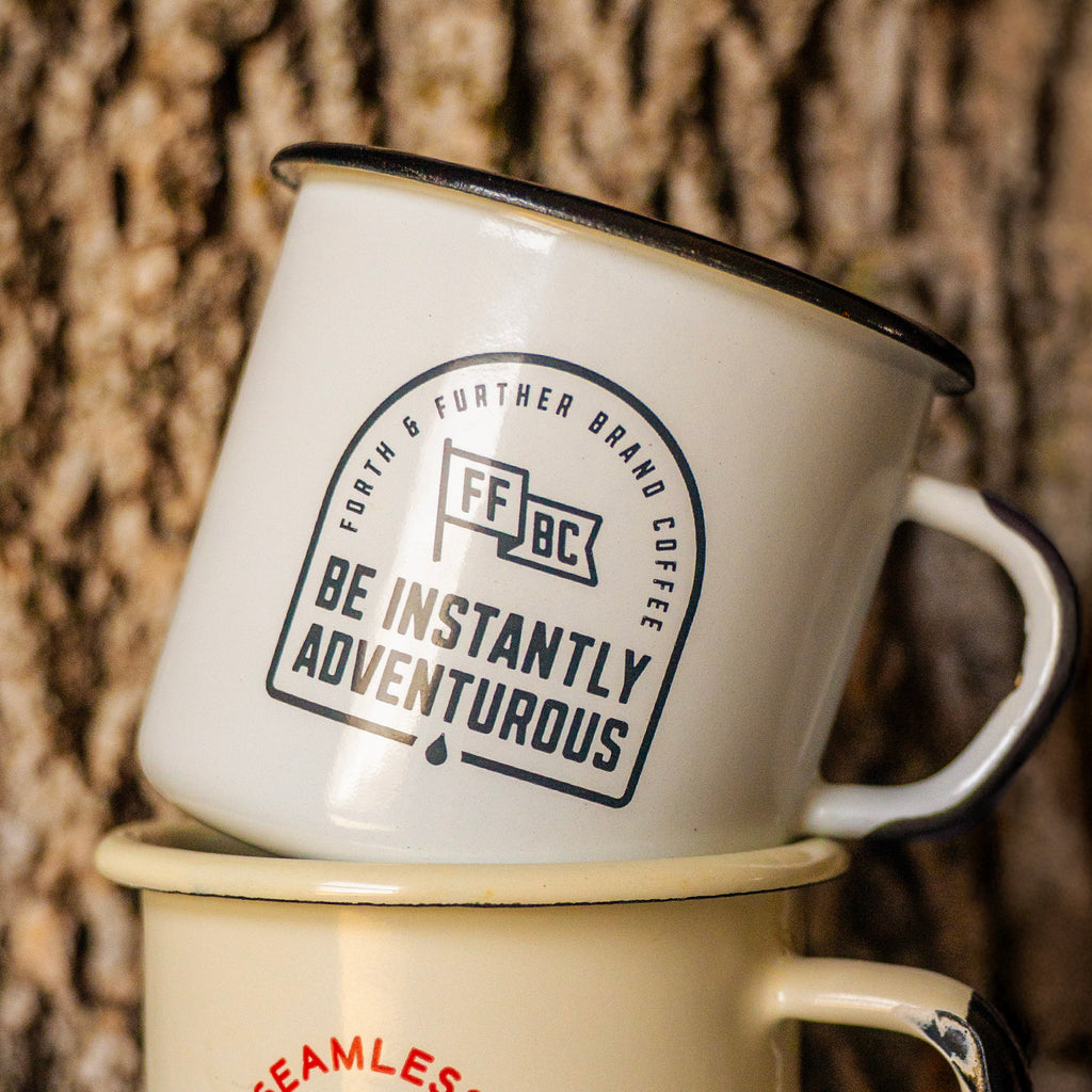 Enamel camp mug with branding against a treebark background
