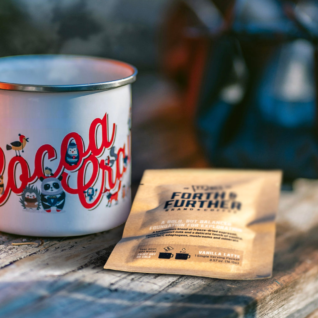 Forth and Further compostable coffee package and enamel camp mug on a wooden surface.