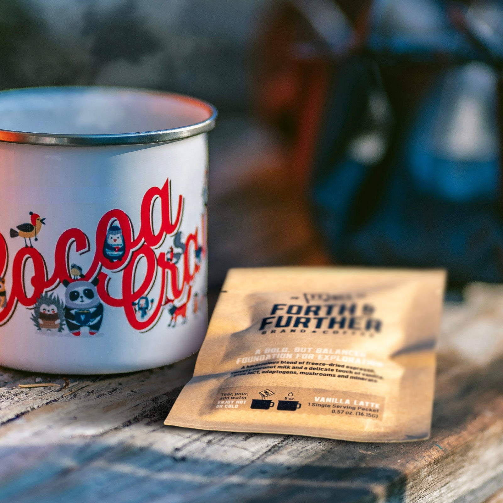 Forth and Further compostable coffee package and enamel camp mug on a wooden surface.