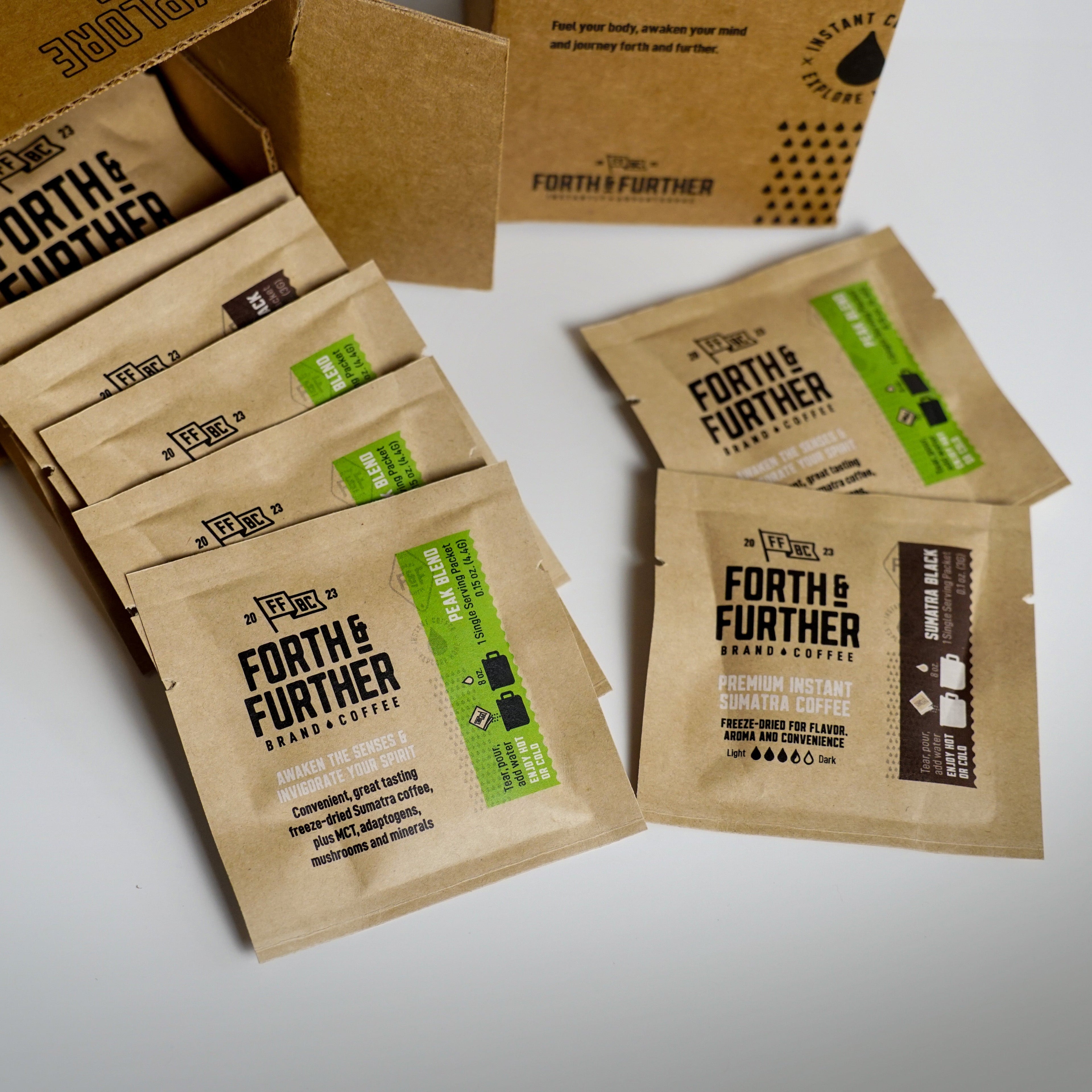 Assortment of Forth & Further compostable coffee packets on a white surface with a recyclable cardboard box in the background.
