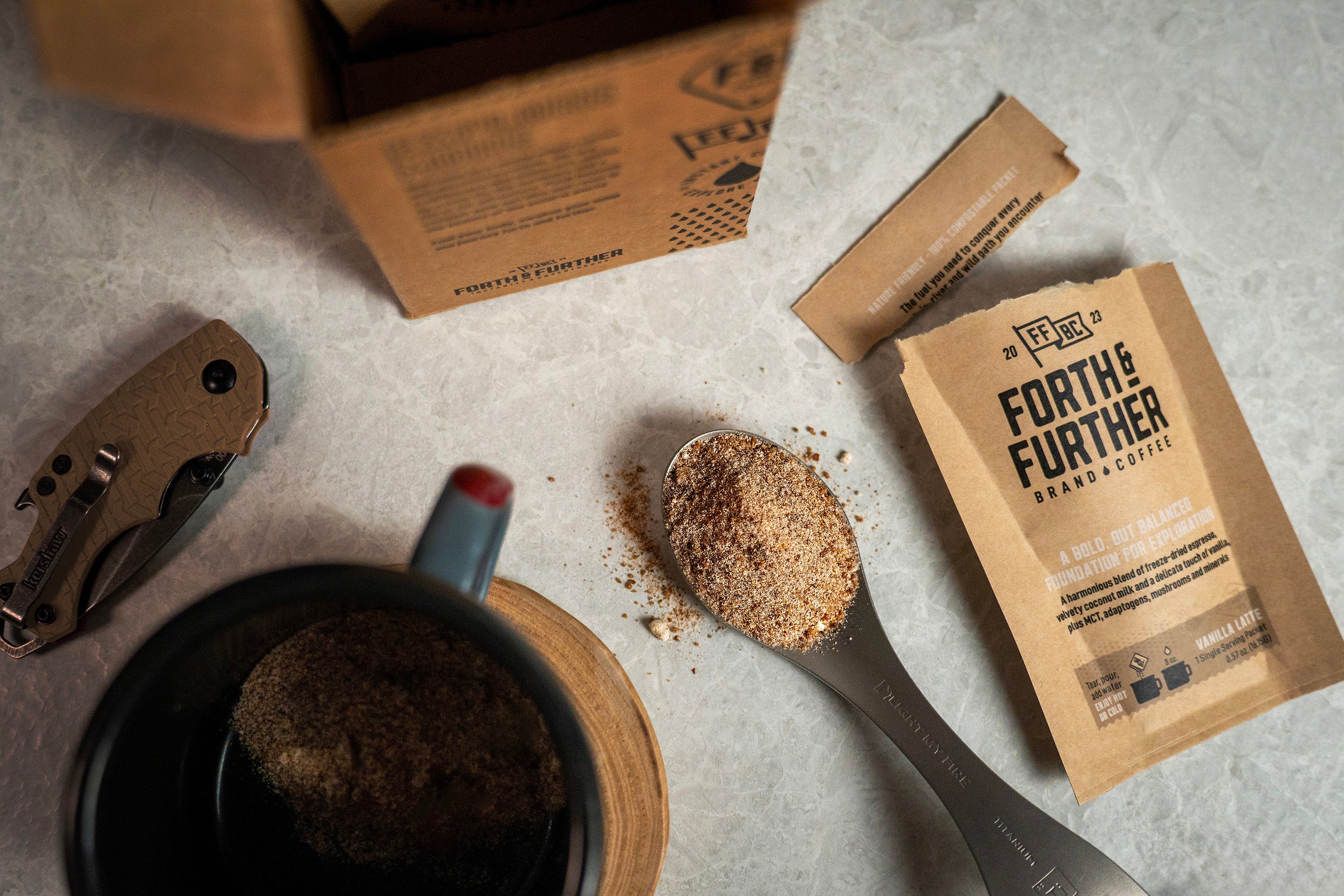 Freeze-dried coffee in a spoon sitting on a counter near a coffee mug and coffee packet